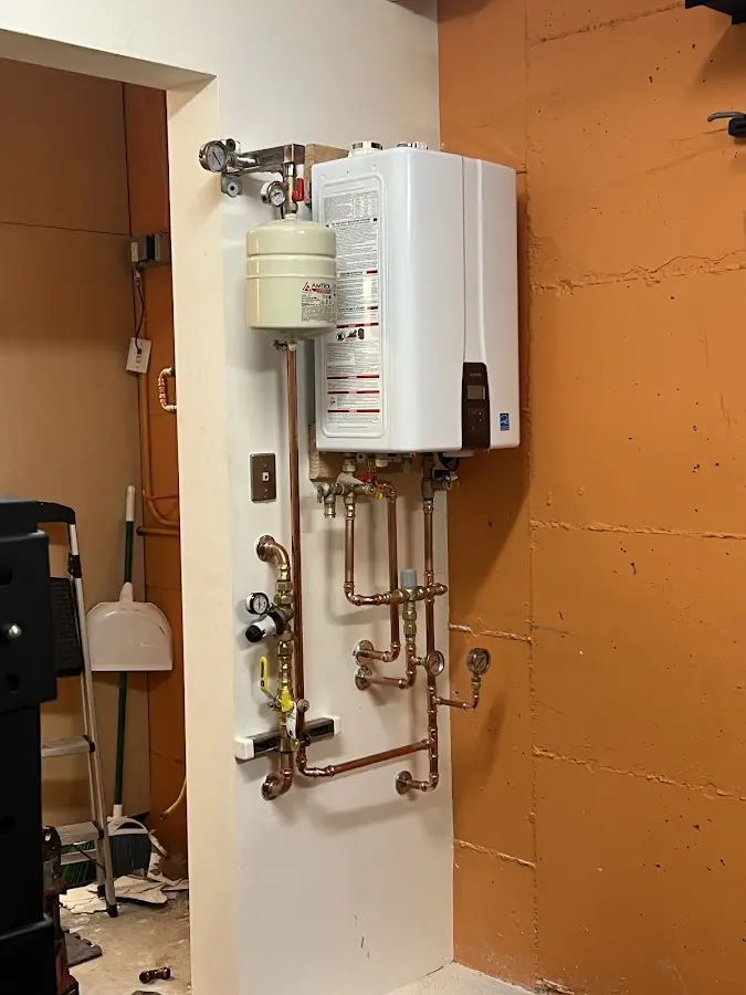 Plumbing technician inspecting water heater connections in Wakefield